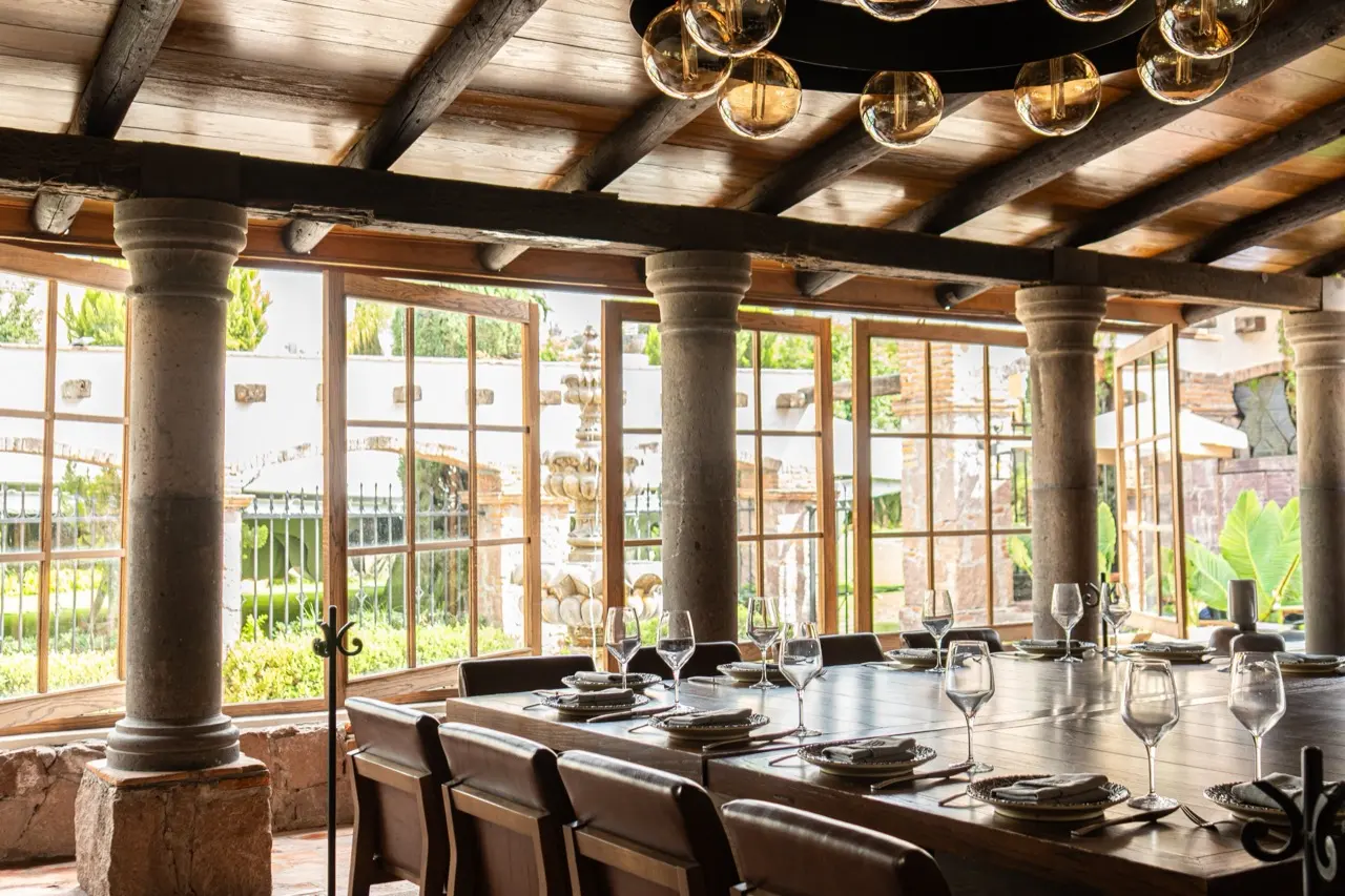 Salón privado techado de Hacienda de Piedra, con vigas de madera, columnas de cantera y mesa larga montada